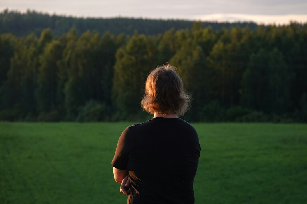 Elderly Polish farmer standing in a field at sunrise